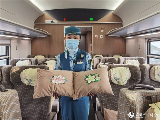 赵莹静展示中老铁路国际旅客列车里带有中国牡丹花和老挝占巴花刺绣图案的靠垫。人民网记者 杜明明摄