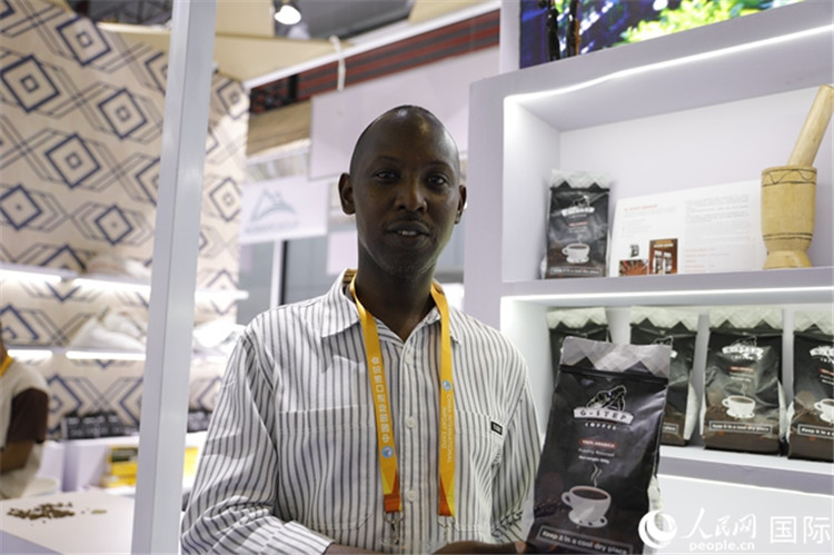 图1：来自卢旺达的进博会参展商安迪展示咖啡豆 人民网记者 李美玉摄