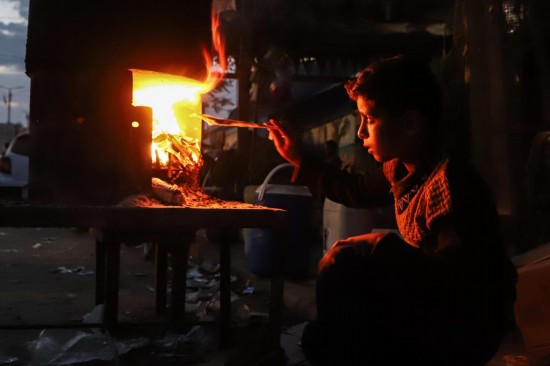 11月11日，一名男孩在加沙地带南部城市汗尤尼斯街头用柴火做饭。新华社发（里泽克·阿卜杜勒贾瓦德摄）