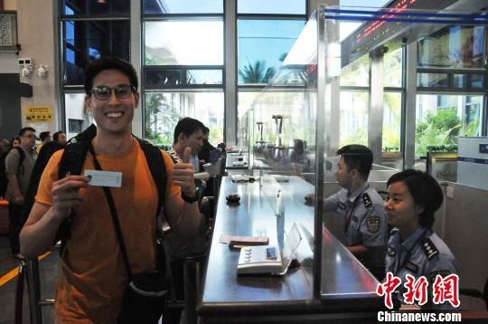  4月30日上午，从美兰机场入境的新加坡旅客接过海口美兰边检站民警的温馨提示小卡片后竖起大拇指点赞。　李柳清　摄