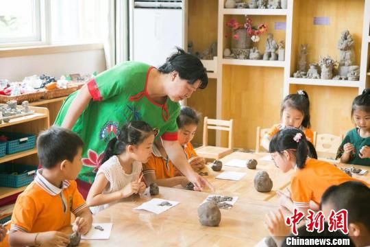 图为刘雪玲正在给幼教中心的孩子上泥塑课。　钟欣 摄