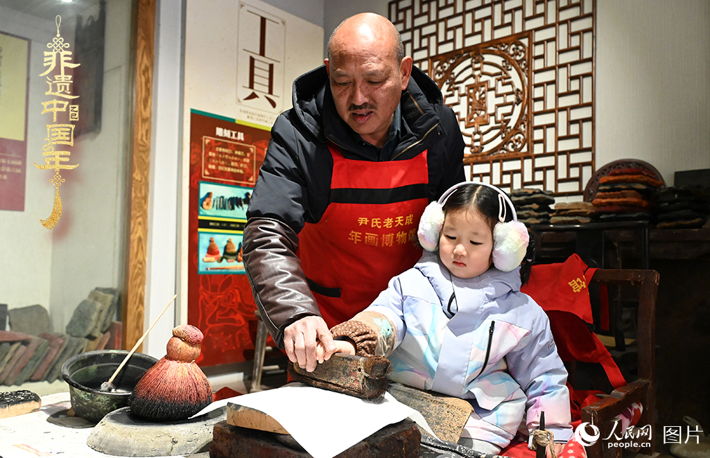 2025年1月27日，河南开封朱仙镇木版年画艺人尹国法指导小朋友研习年画印制技艺。朱仙镇木版年画源自汉唐壁画艺术，是中国木版年画的鼻祖。2006年5月20日，朱仙镇木版年画经国务院批准列入第一批国家级非物质文化遗产名录。人民网记者 王玉兴摄