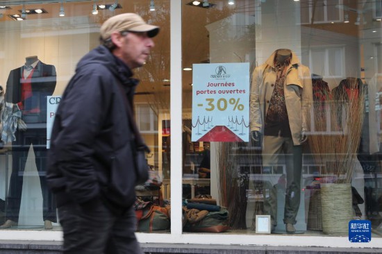   10月31日，一名男子从比利时布鲁塞尔一家贴有打折信息的店铺前走过。新华社记者 赵丁喆 摄