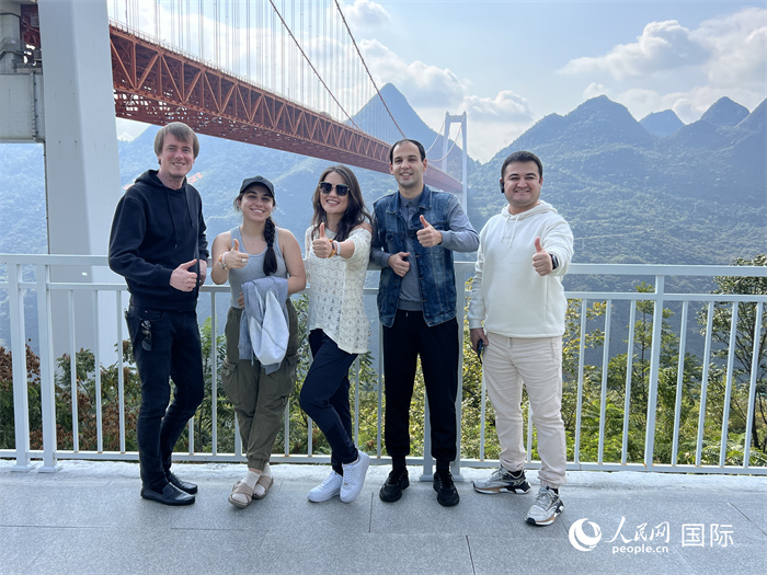 欧亚国家记者在坝陵河大桥下合影,并给大桥“点赞”。人民网 花放摄