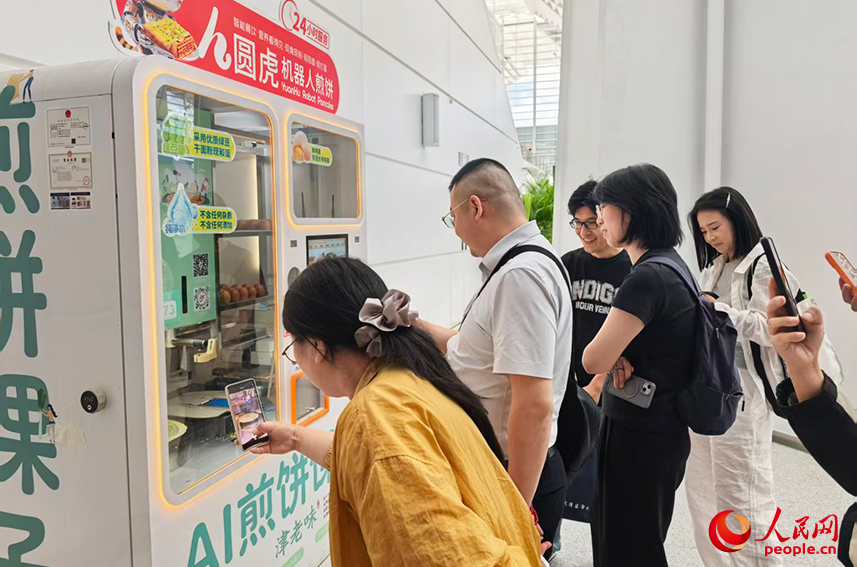 2026世界智能产业博览会上，煎饼馃子机器人前，排起了长队。人民网记者 陶建摄