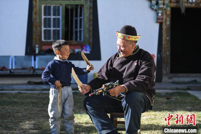 图为米林县扎西绕登乡彩门村64岁的洛桑带着孙子巴桑在院子的草地上玩耍。　何蓬磊 摄