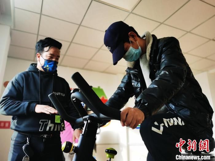 图为尖扎县残疾人托养服务中心负责人张财指导一名残疾人骑动感单车。 张添福 摄