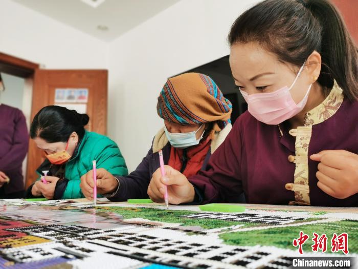 图为工作人员和残疾人共同制作手工作品。 张添福 摄