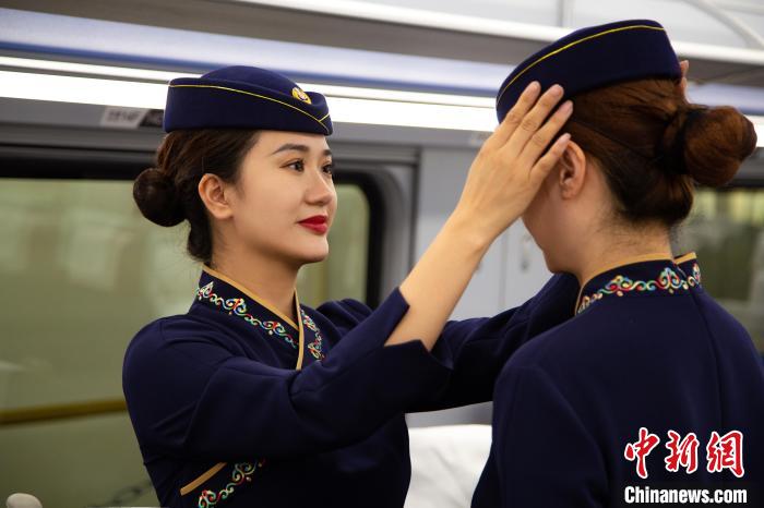 图为青藏铁路西格段“复兴号”动车组乘务员互相整理新制服。　李磊 摄