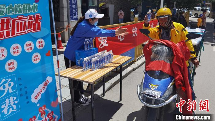 图为近日，西藏自治区青年志愿者协会志愿者在拉萨街头向快递员送水。西藏自治区青年志愿者协会 供图