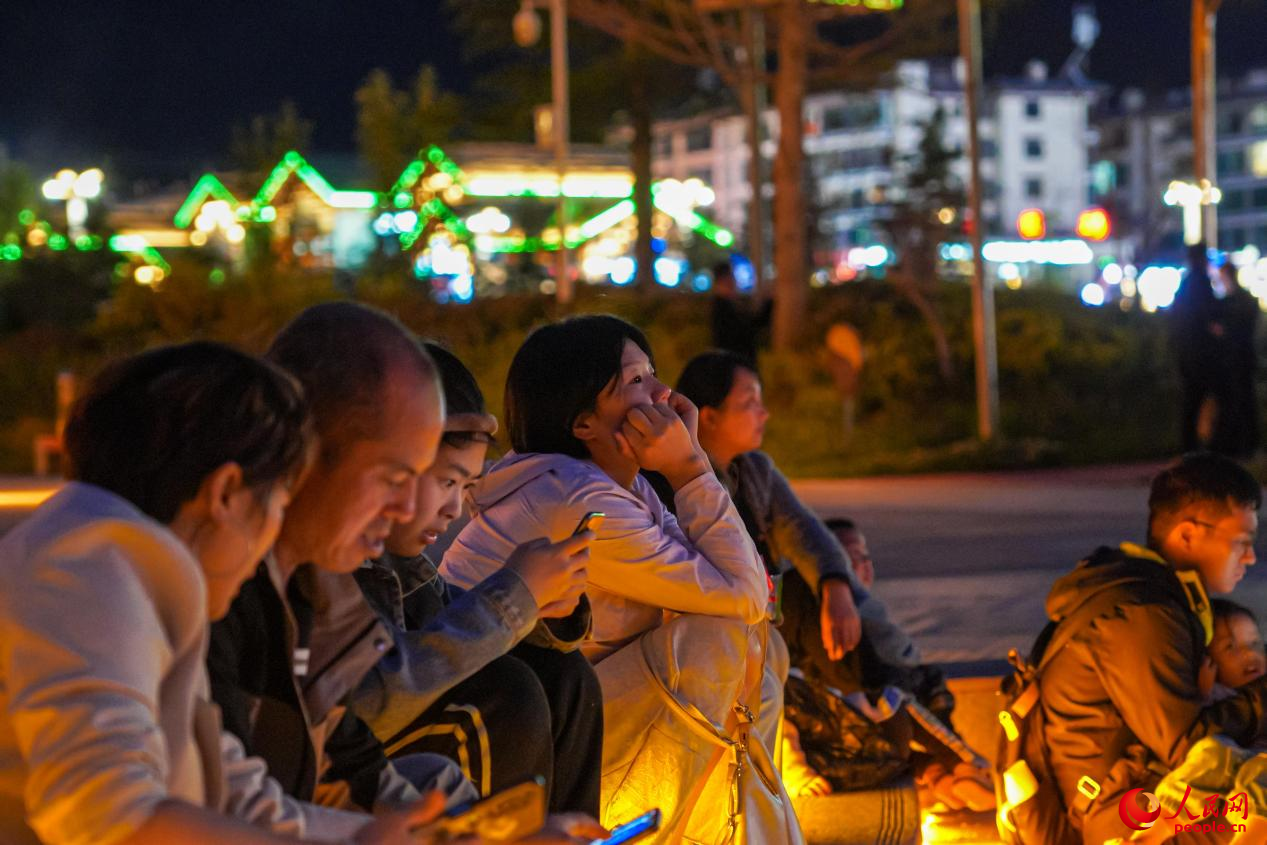 市民坐在西藏林芝市民族团结广场台阶上欣赏音乐喷泉。人民网记者 赵晨摄