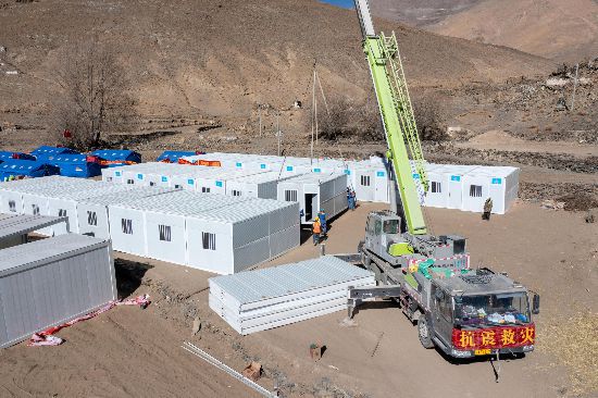 2025年1月9日,在定日县长所乡古荣村安置点,救援人员和施工人员合力抓紧搭建移动板房,确保受灾群众温暖过冬。人民网记者 翁奇羽摄