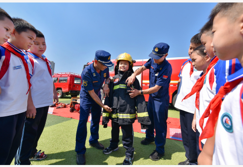 8月31日，在山东邹平市黄山实验小学，小学生体验穿着消防救援服。 新华社发  李晓伟 摄